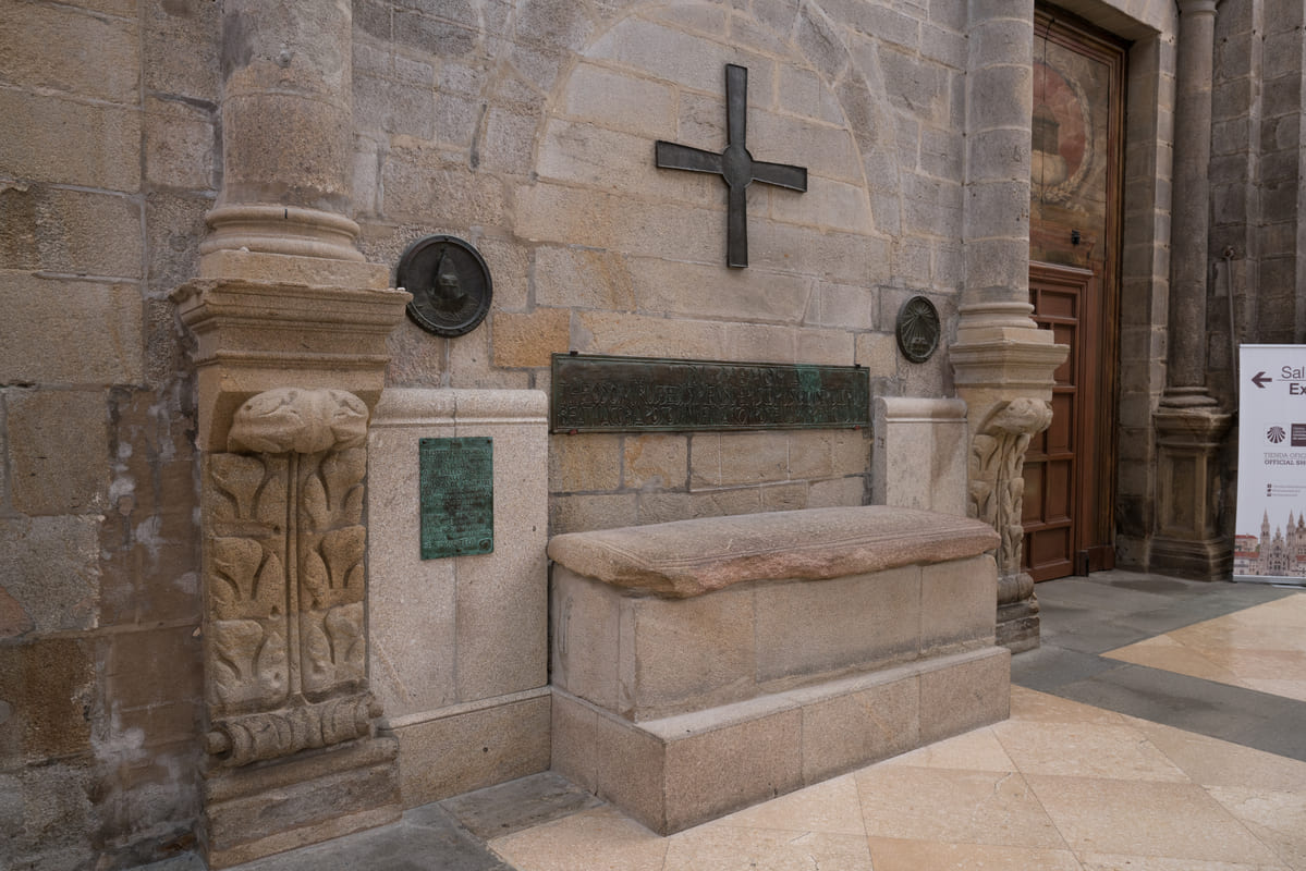 Lauda sepulcral del obispo Teodomiro en el brazo sur del crucero de la Catedral de Santiago, junto a una gran cruz de bronce y su placa con la inscripci&oacute;n original