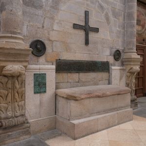 Lauda sepulcral del obispo Teodomiro en el brazo sur del crucero de la Catedral de Santiago, junto a una gran cruz de bronce y su placa con la inscripción original