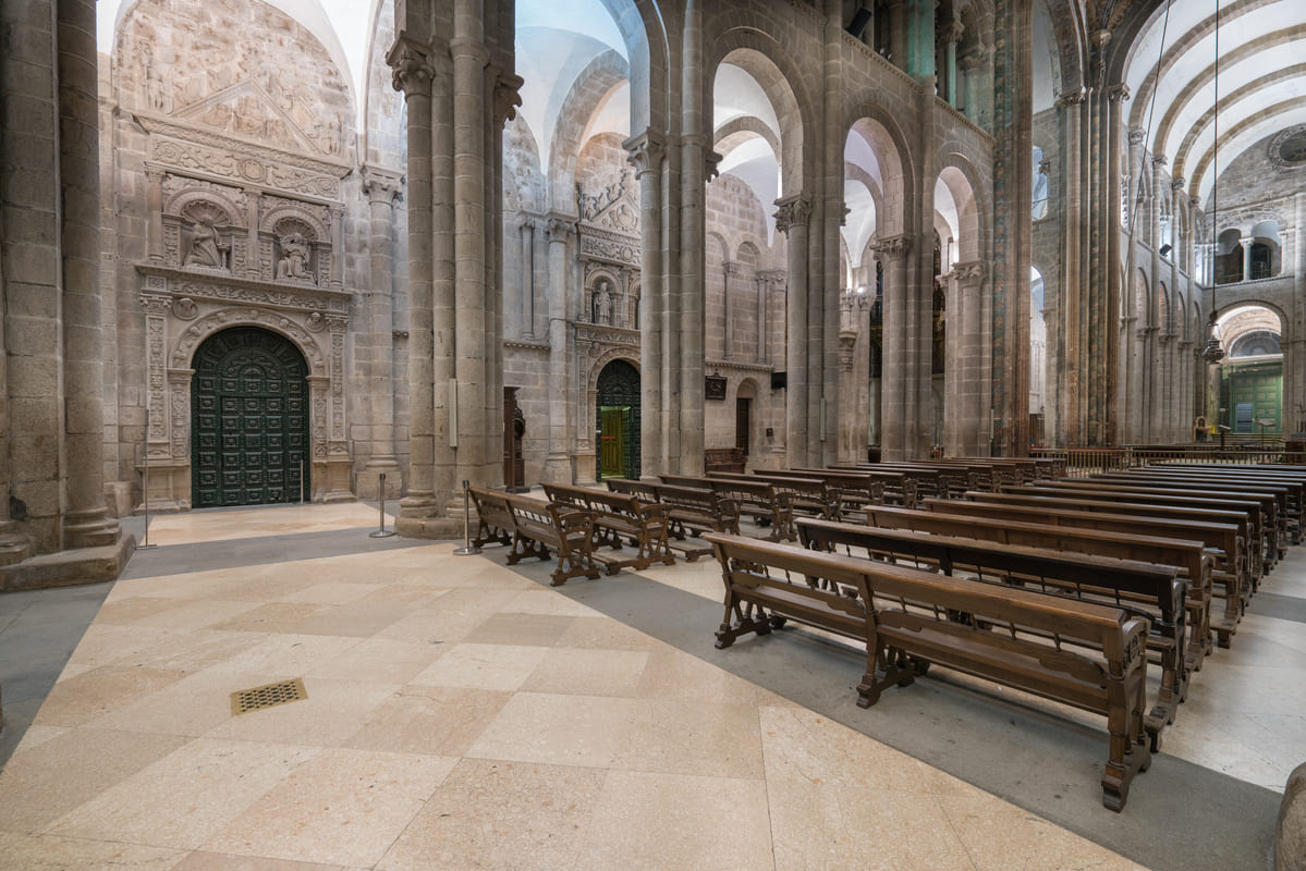 Puertas platerescas de acceso al claustro y a la sacrist&iacute;a en el brazo sur del crucero, entre las columnas rom&aacute;nicas de la Catedral de Santiago