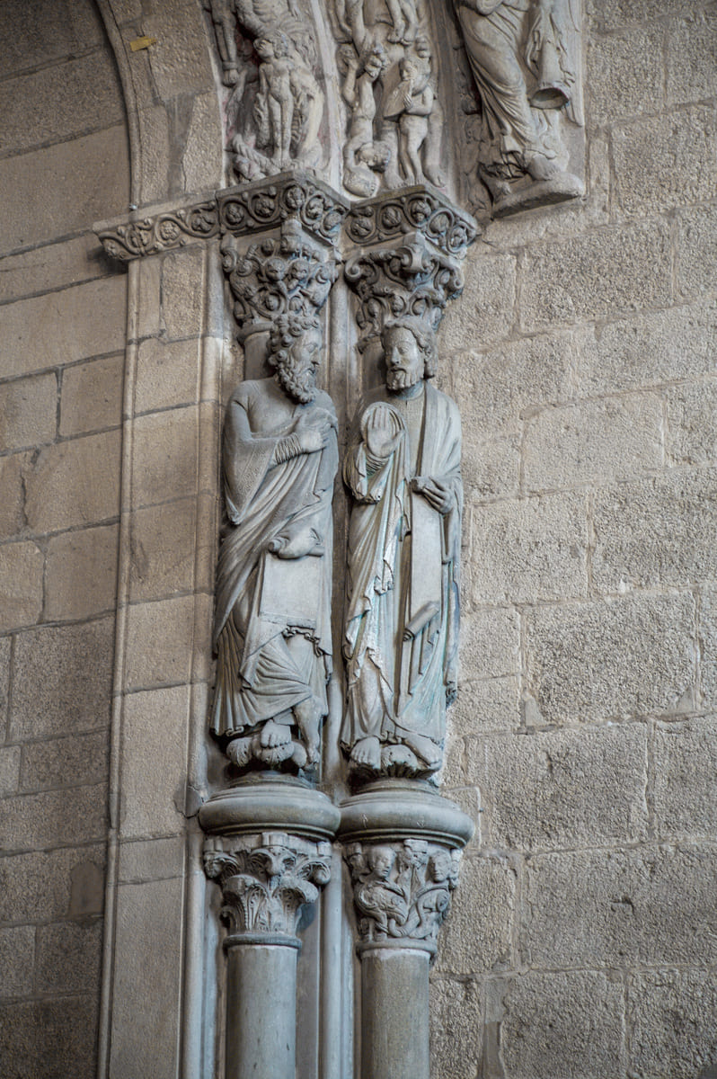 Estatuas-columna del arco sur del P&oacute;rtico de la Gloria con capiteles historiados, junto a las figuras del Juicio Final y un &aacute;ngel con las trompetas del Apocalipsis