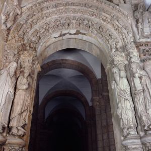 Arco lateral del Pórtico de la Gloria sin tímpano, con las arquivoltas pobladas de figuras y un óculo de la bóveda del nártex sobre él