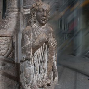 Figura arrodillada del Santo dos Croques en el Pórtico de la Gloria, considerada el autorretrato del Maestro Mateo, con el desgaste de siglos de cabezazos rituales de los estudiantes